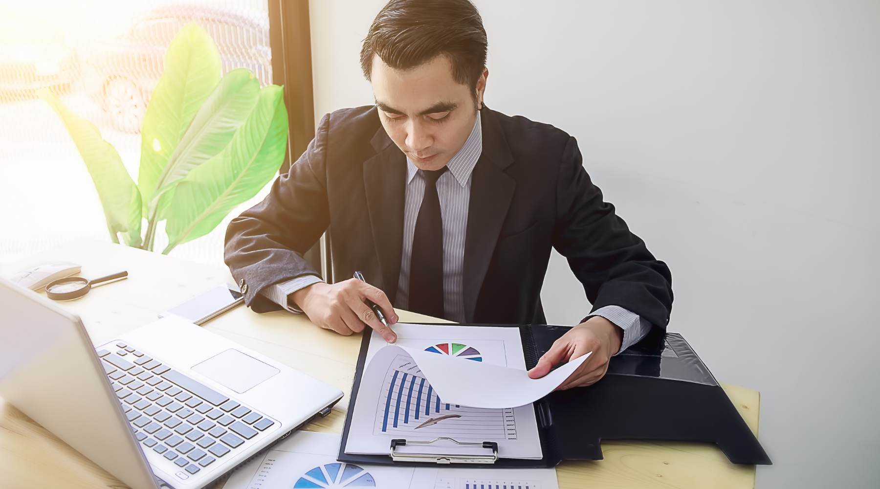 Professional man in a business suit analyzing financial charts and graphs at a desk with a laptop, symbolizing data-driven decision-making and ROI strategy.