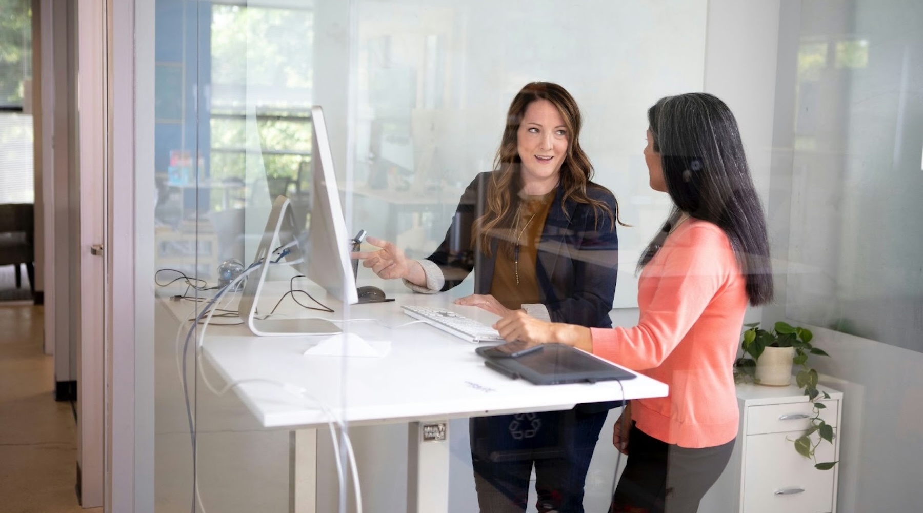 An image of an Executive Assistant working strategically with her executive at a standing desk in front of a computer.